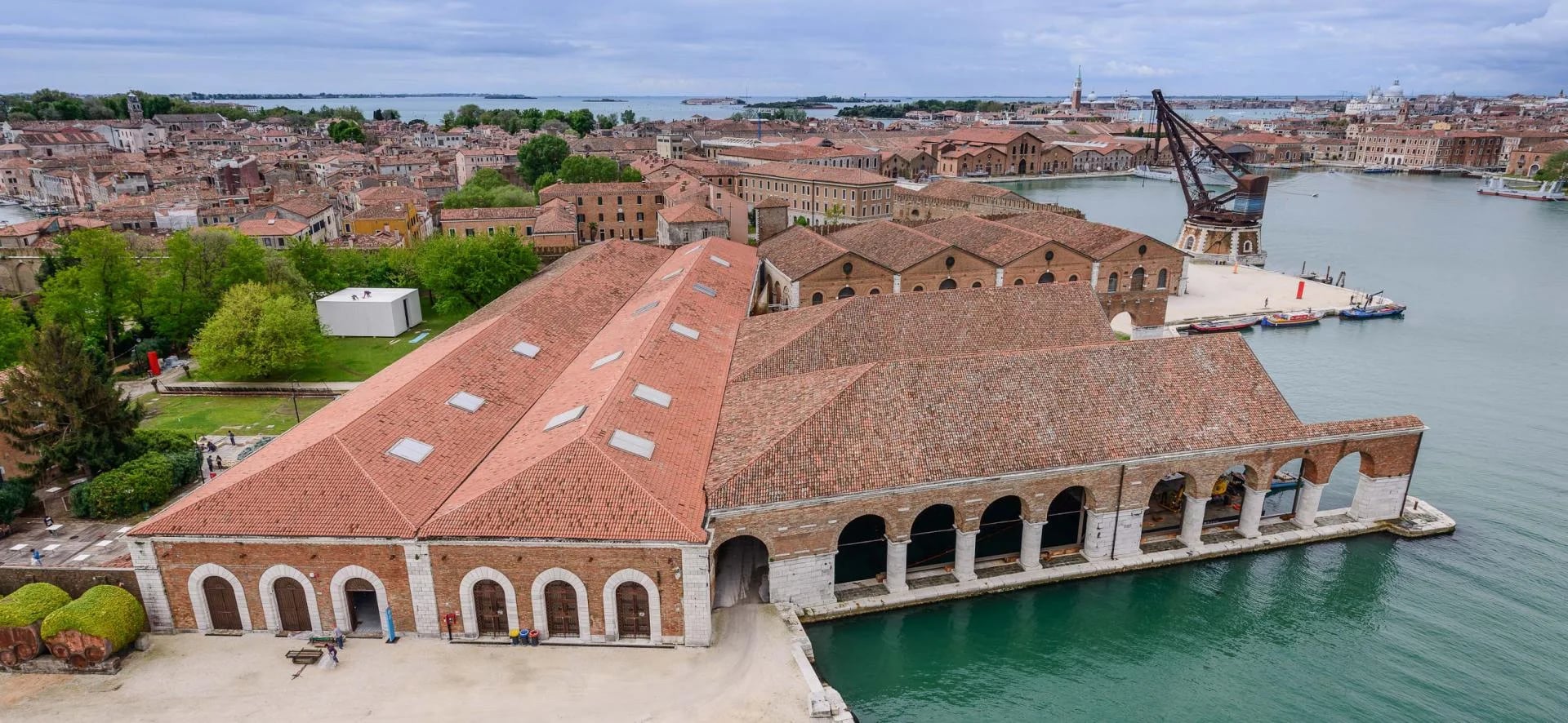 Aerial view of the Arsenale exhibition halls in Venice, surrounded by water and historic buildings, one of the main venues of the Venice Biennale.